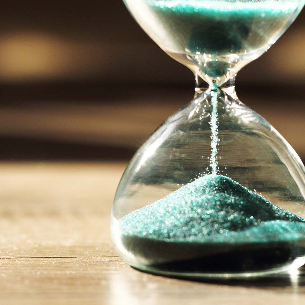 Hour glass with green sand in it on a table